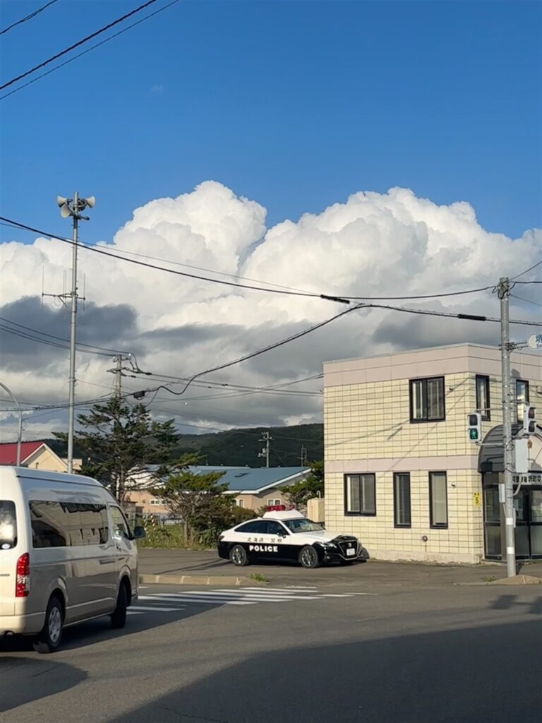 青空と入道雲の下、パトカーが停まる浦河の交差点
