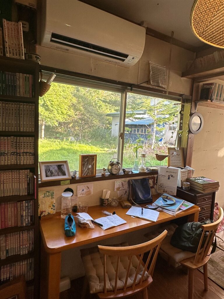 本棚と机のある部屋と、窓の外の緑